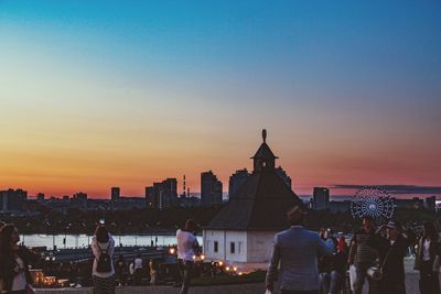 People in city against sky during sunset