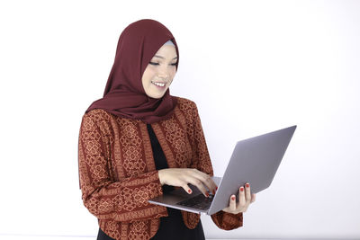 Young woman holding smart phone against white background