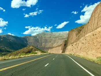 Empty road by mountains against sky