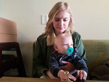 Portrait of happy mother holding baby sitting at home