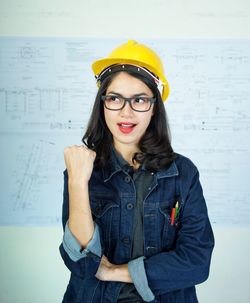 Portrait of young woman standing against wall