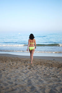 Young woman standing at beach against clear sky