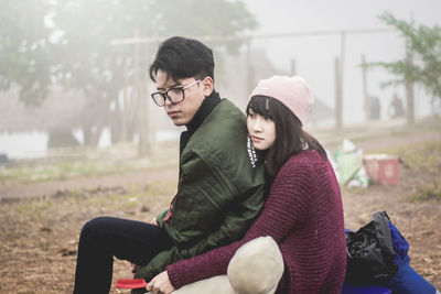 Young couple sitting in park during winter