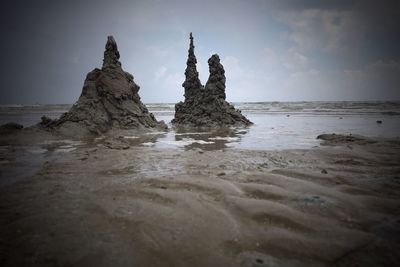 Rock formation on beach against sky