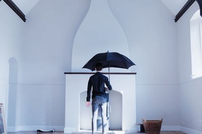 Rear view of man holding umbrella