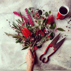 Directly above shot of hand holding red rose on table