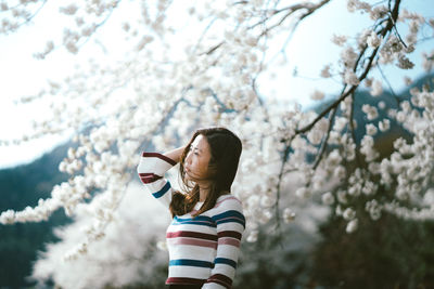 Low section of woman with arms raised against trees