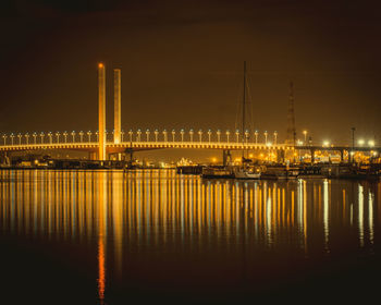 Illuminated bridge over river against sky at night
