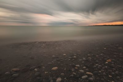 Close-up of pebbles on beach against sky during sunset