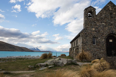 Building by lake against cloudy sky