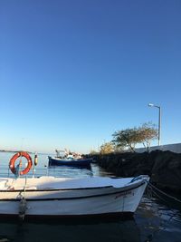 View of fishing boats in sea against clear blue sky