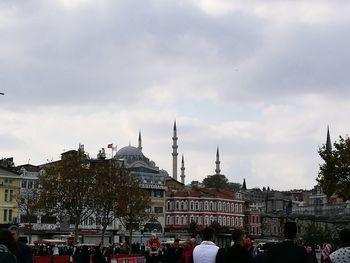 Crowd in city against sky