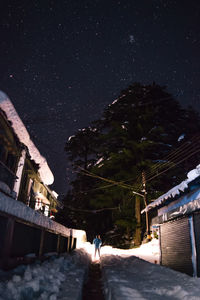 Rear view of people on illuminated building against sky at night