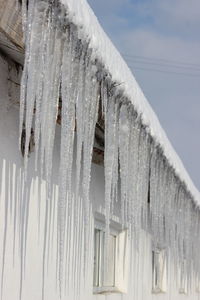 Low angle view of icicles on roof against sky