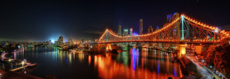 Illuminated bridge over river at night