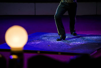 Low section of person standing on illuminated ball