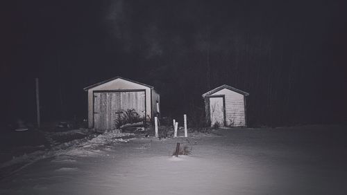 Man in illuminated house against sky at night