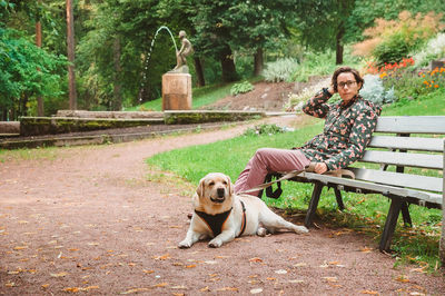 Portrait of woman with dog sitting on bench in park
