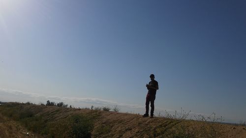 Full length of man standing on hill against clear sky
