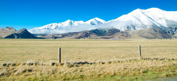 Scenic view of field and mountains against clear blue sky