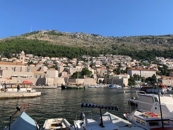 Sailboats moored in sea by town against clear sky