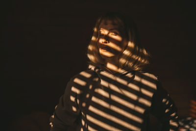 Portrait of young woman looking away against black background