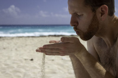 Close-up of man blowing sand at beach