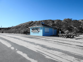 Road by building against clear blue sky