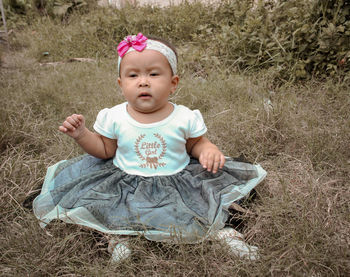 High angle view of cute baby girl sitting on land