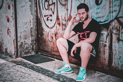 Full length of young man sitting on wall