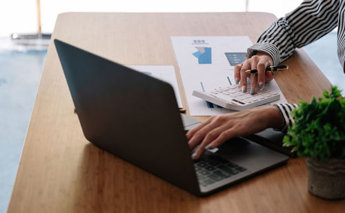 Midsection of businessman using laptop on table