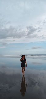 Full length of woman standing on beach against sky