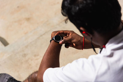 Man holding watch sitting outdoors