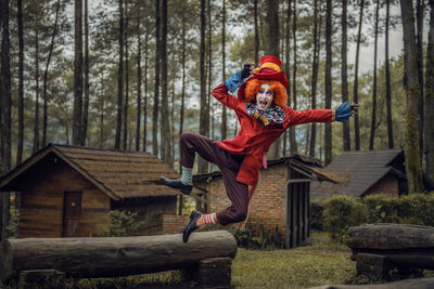 Portrait of man wearing costume jumping against cottage