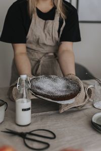 Woman putting freshly baked chocolate cake on table