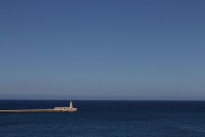 Sailboat in sea against clear blue sky