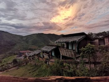 Abandoned house by mountains against sky during sunset