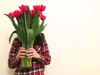 Woman holding red flower against white background