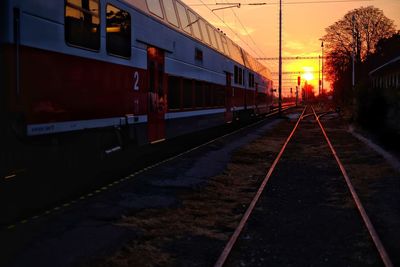 Train at railroad station against sky during sunset