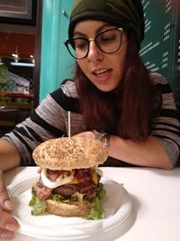 Young woman having burger at table in restaurant