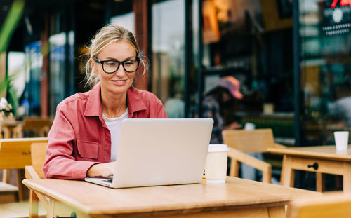 Young woman using laptop at cafe