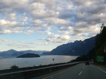 Road by mountains against sky