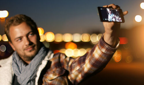 Young man taking selfie outdoors at night