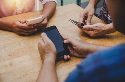 Midsection of man using smart phone on table