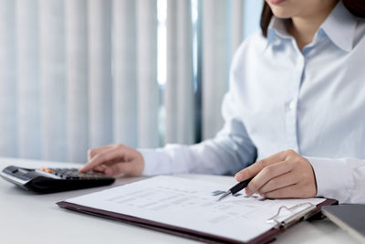 Midsection of businesswoman working on table