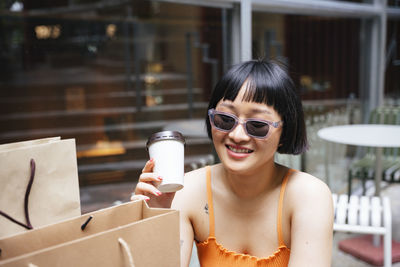 Portrait of a smiling young woman holding camera