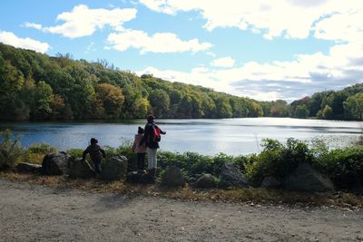 Men sitting on lake against sky