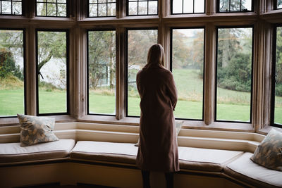 Rear view of woman looking through window