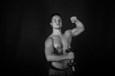 Portrait of shirtless young man holding black background