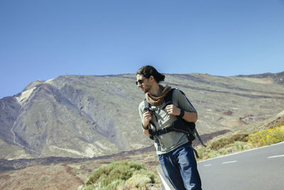 Man standing on mountain road against clear sky